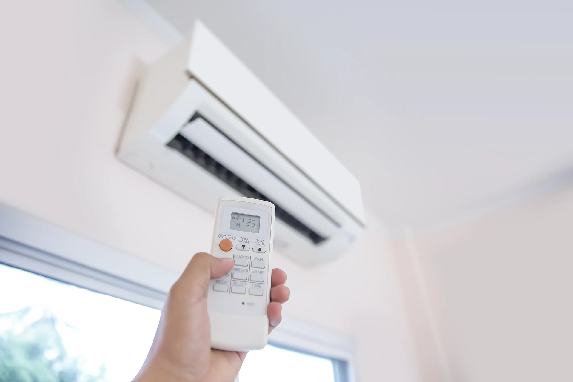 Heat pump servicing – Someone holding a remote up to a heat pump